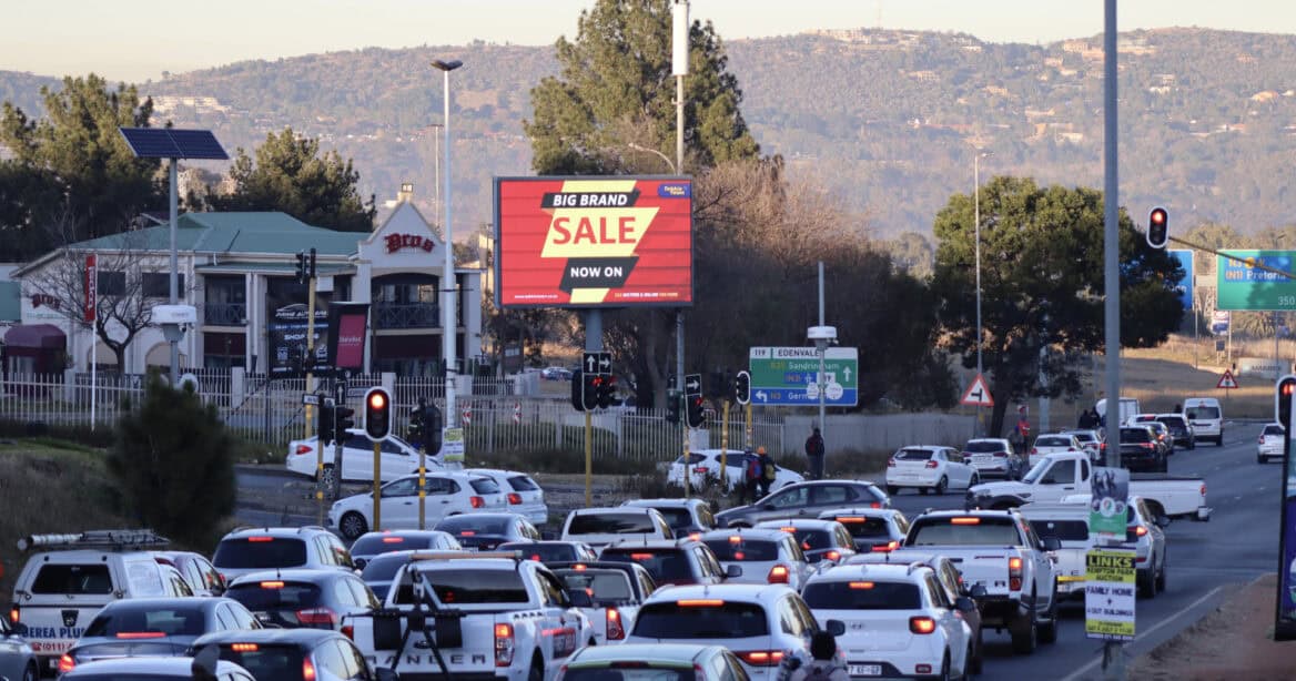 an electronic billboard next to the highway with lots of cars on the road