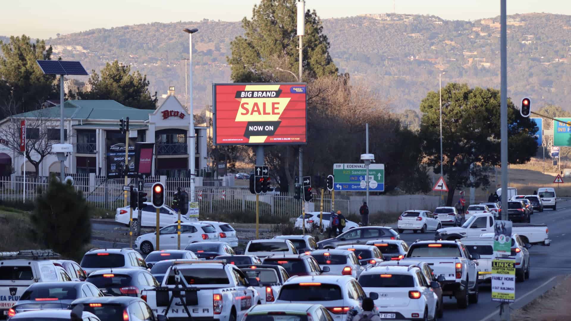 an electronic billboard next to the highway with lots of cars on the road